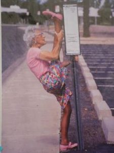 Elderly women with one leg stretched up onto lightpost