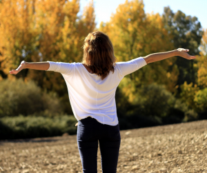 Women outside with arms in air, practicing breathing