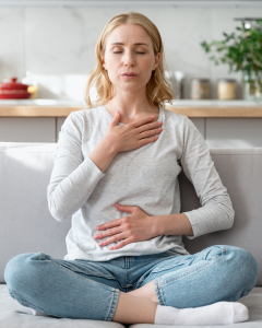 Women sitting breathing, with hand on chest and hand on stomach