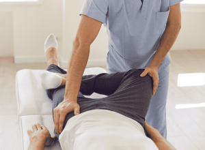 Physiotherapist assessing hip movement of client laying on their back