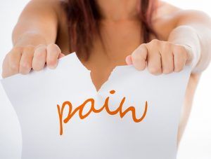 Person ripping a piece of paper, that has the word 'pain' written on it