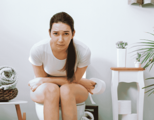 Women on toilet, struggling with constipation